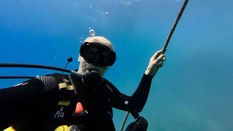 A scuba diver gripping a descent line underwater during a dive