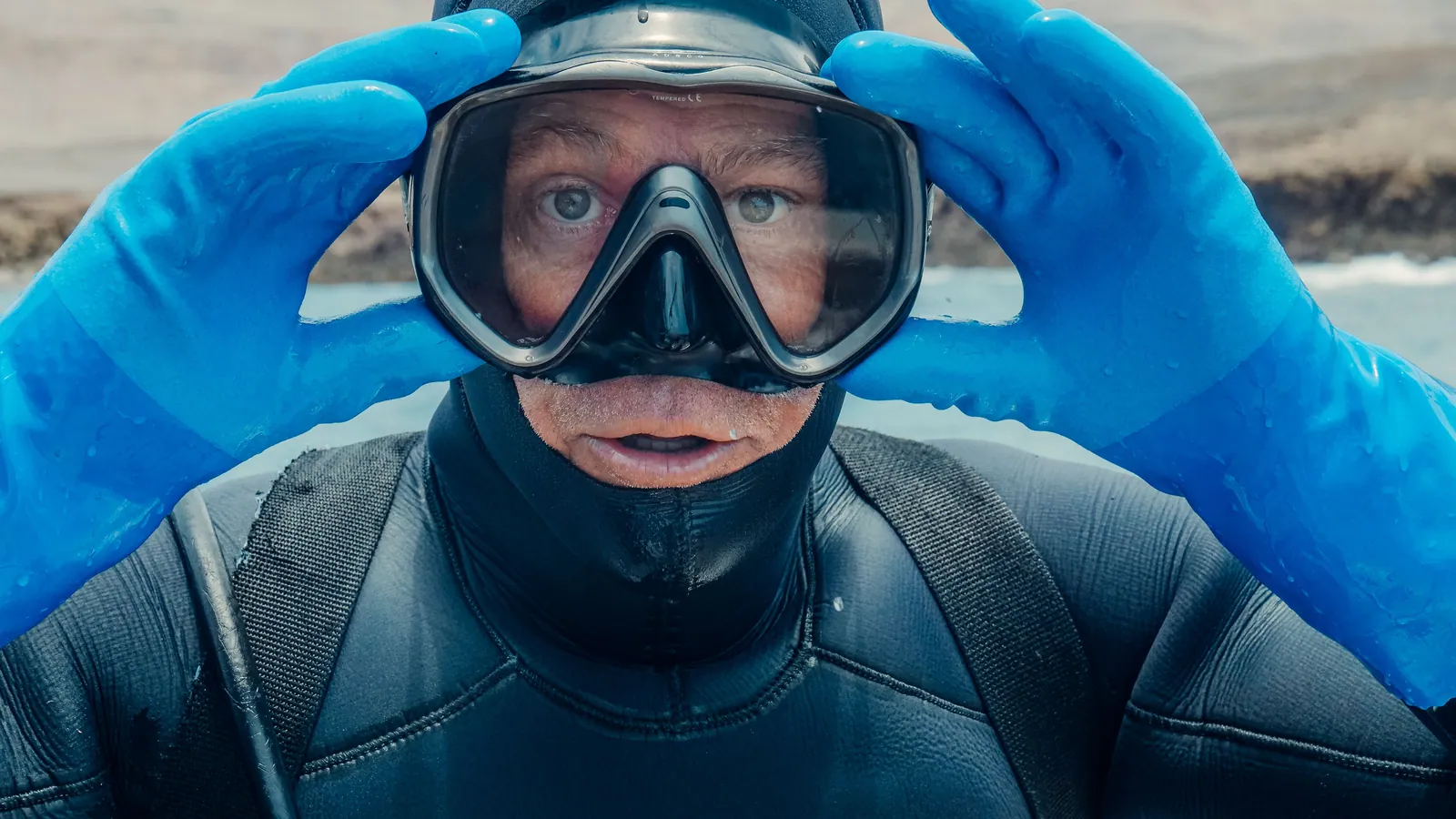 A diver holding a mask against their face to check the fit