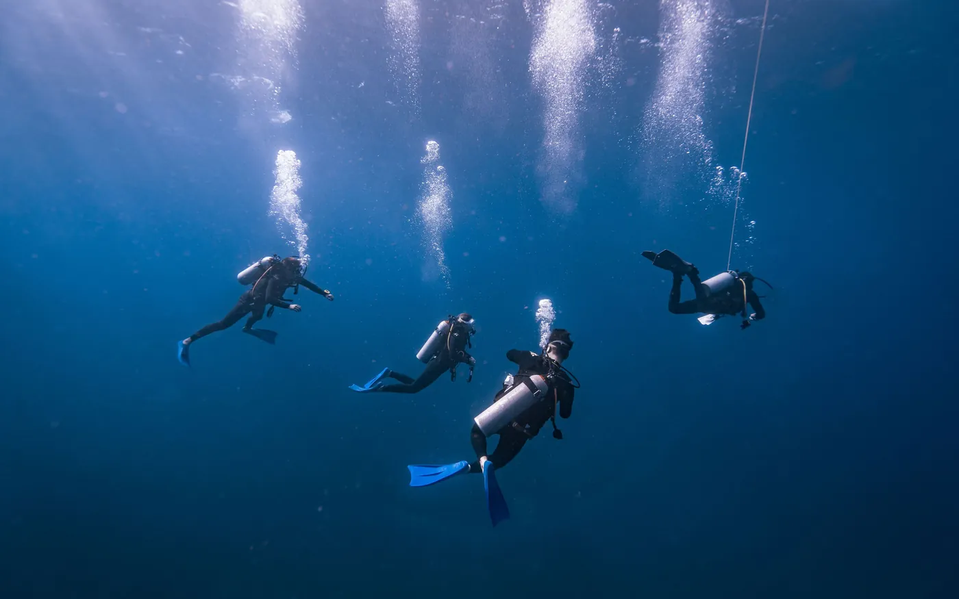 A group of scuba divers underwater with exhaust bubbles rising