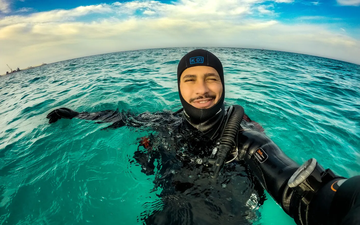 A diver in a hood and full wetsuit at the surface after a dive