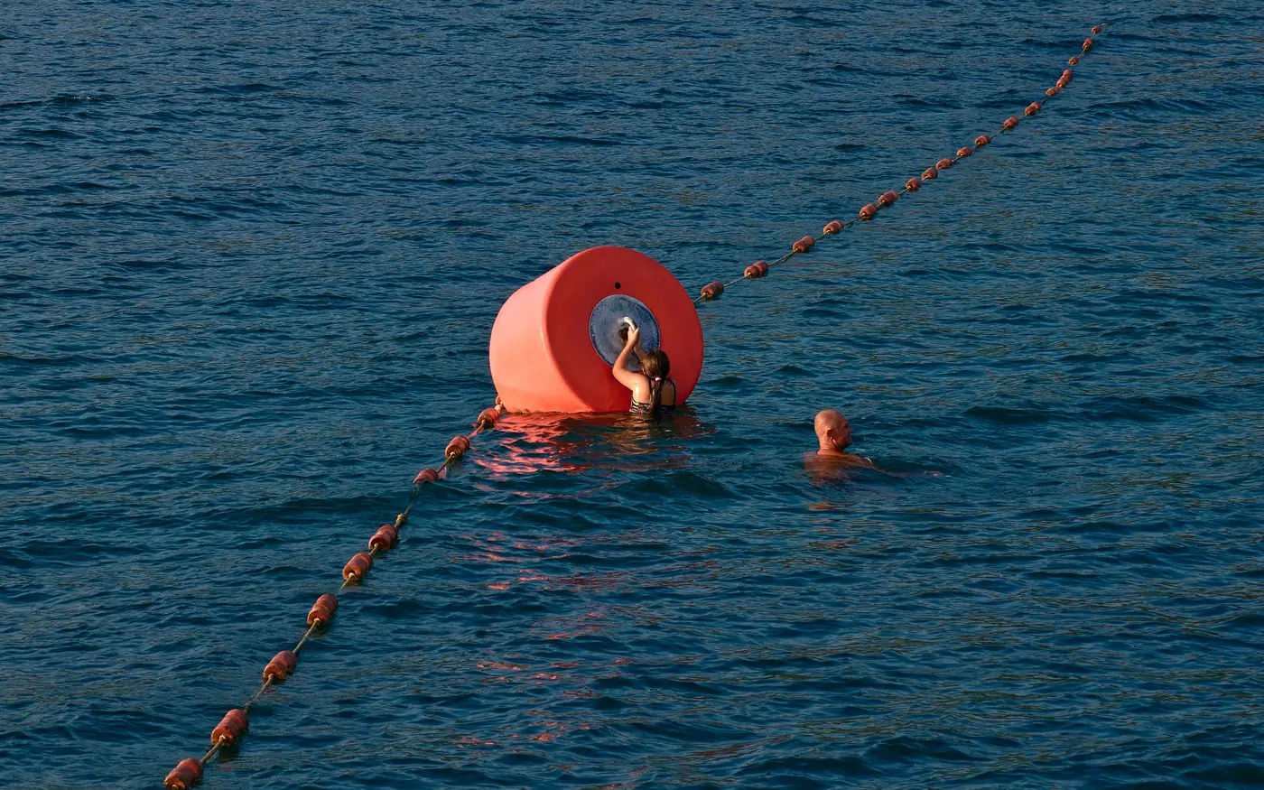 A large marker buoy on a line with a swimmer alongside