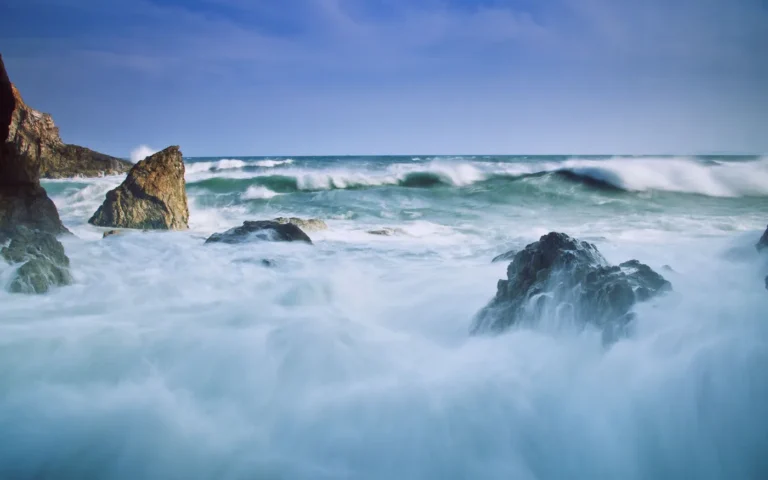 A long exposure of surf washing over shoreline rocks