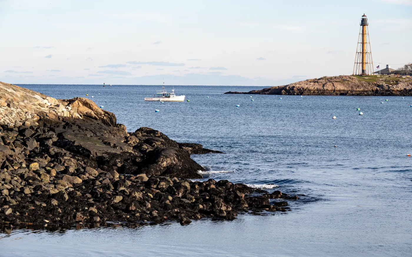 The rocky coast at Marblehead, Massachusetts, with a lighthouse and a moored boat