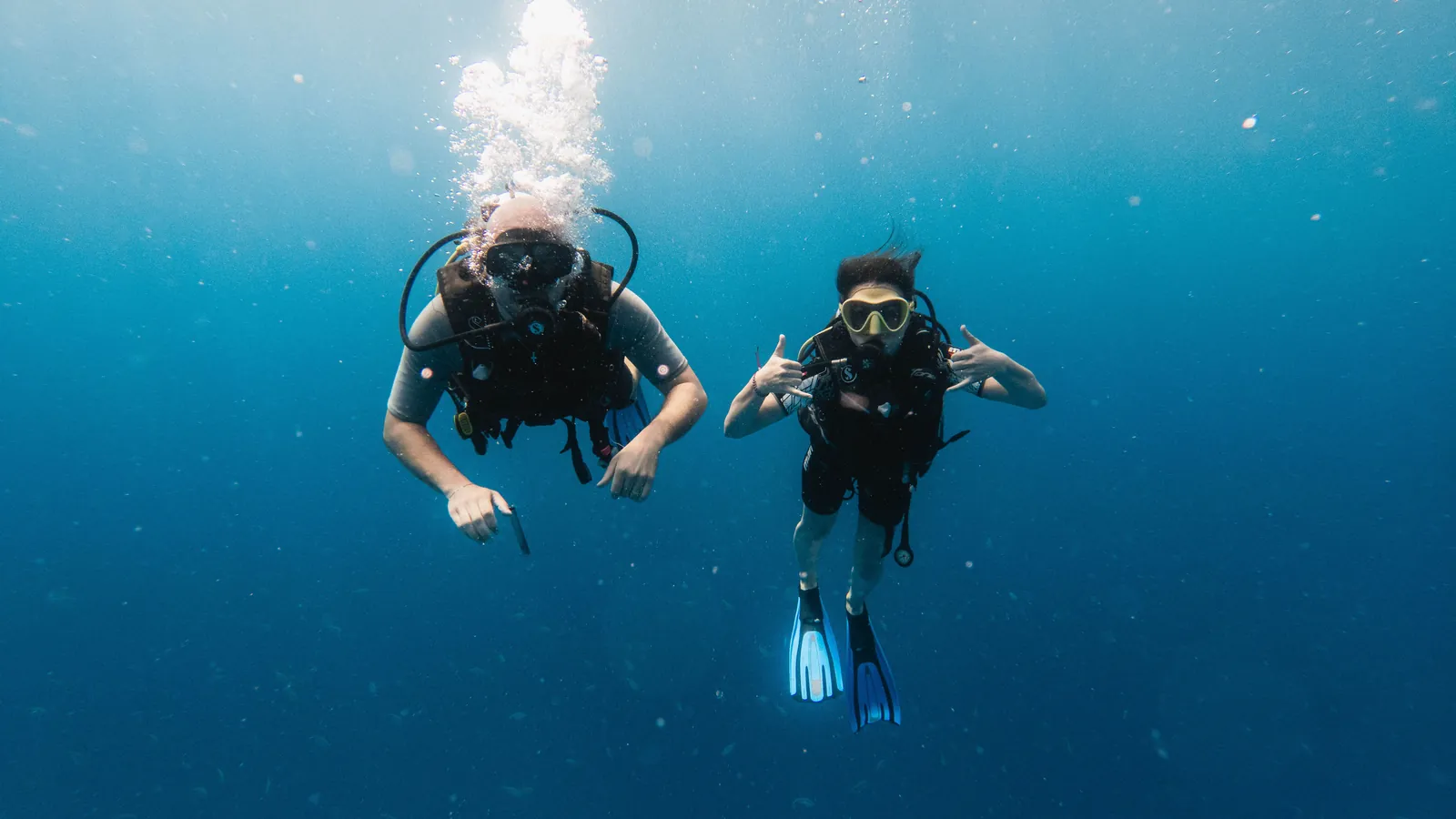 Two scuba divers swimming side by side in clear blue water