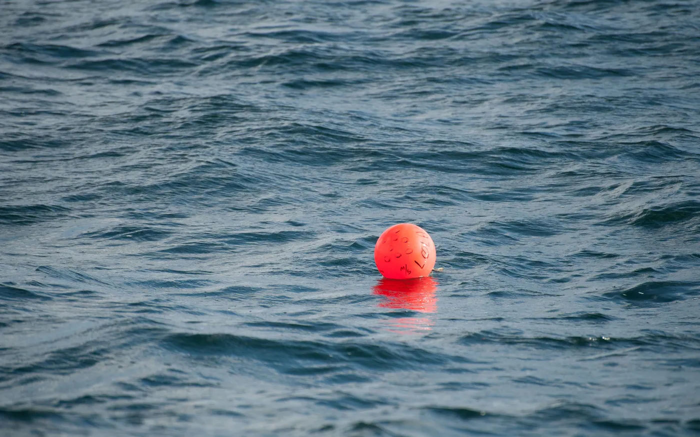 An orange marker buoy floating in open water