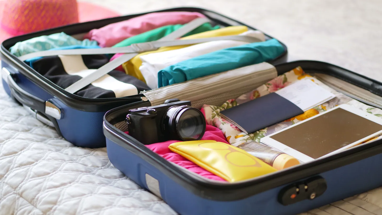 An open suitcase packed for a trip on a bed