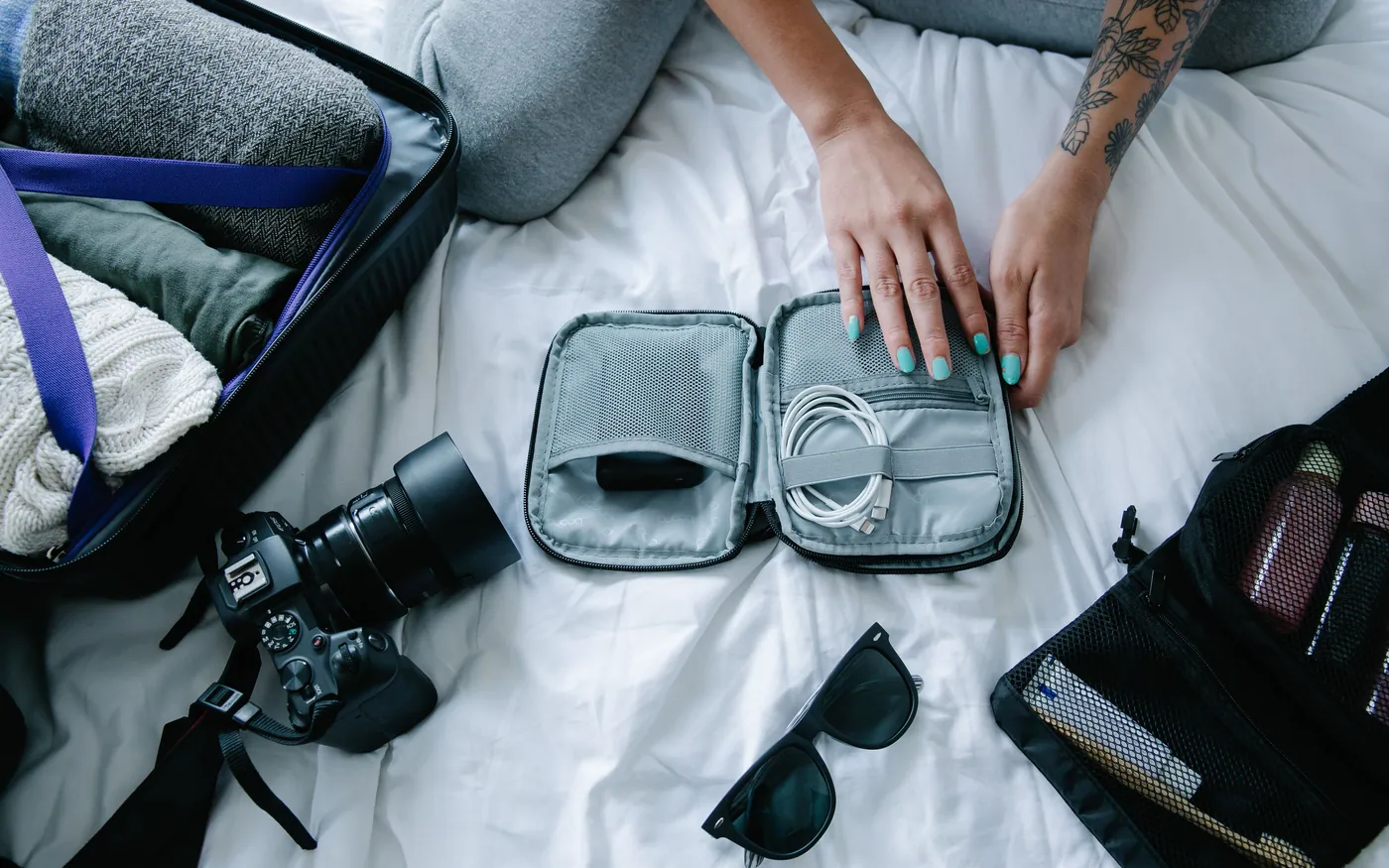 Packing cubes, a camera and sunglasses laid out before packing