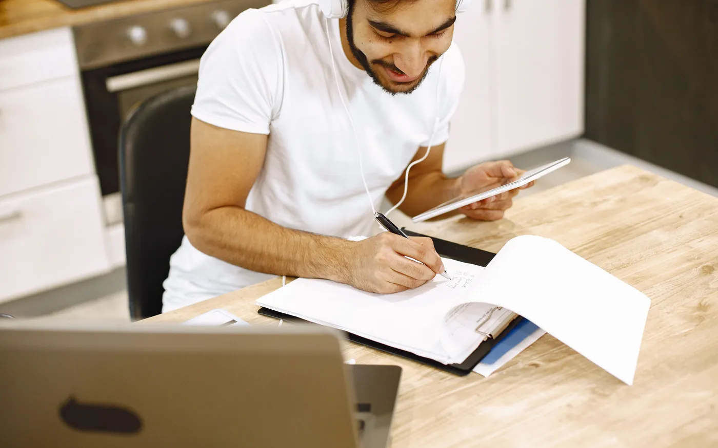 A student taking notes from a tablet and laptop while working through dive theory at home