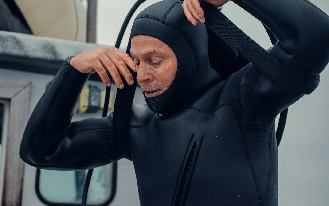 A diver pulling on a neoprene hood before entering the water