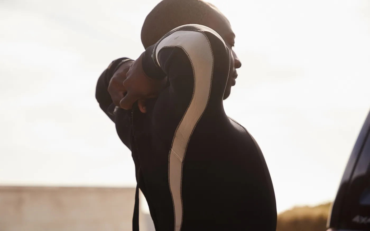 A diver pulling on a wetsuit before entering the water