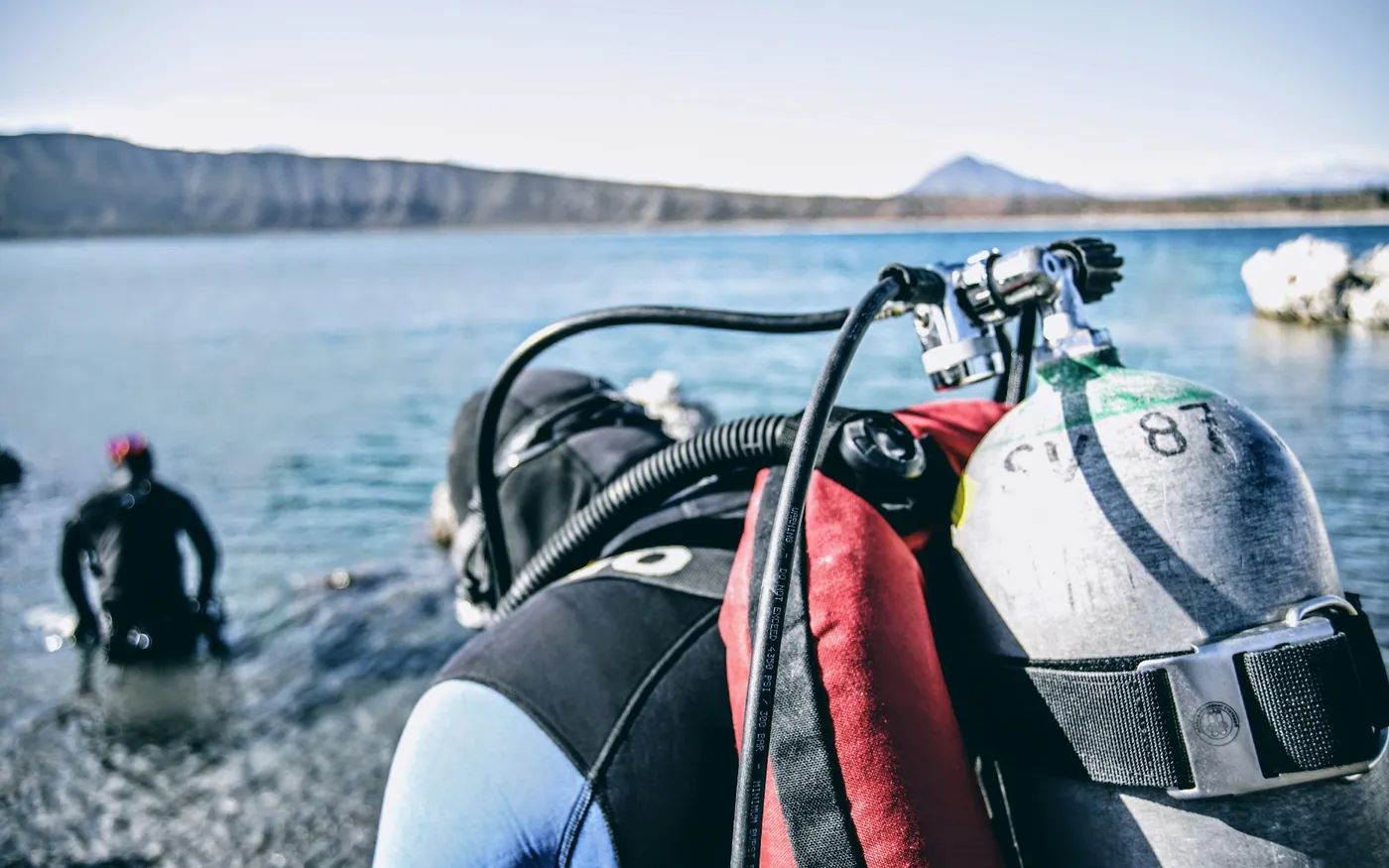 A scuba cylinder, BCD and regulator hoses ready at the water's edge