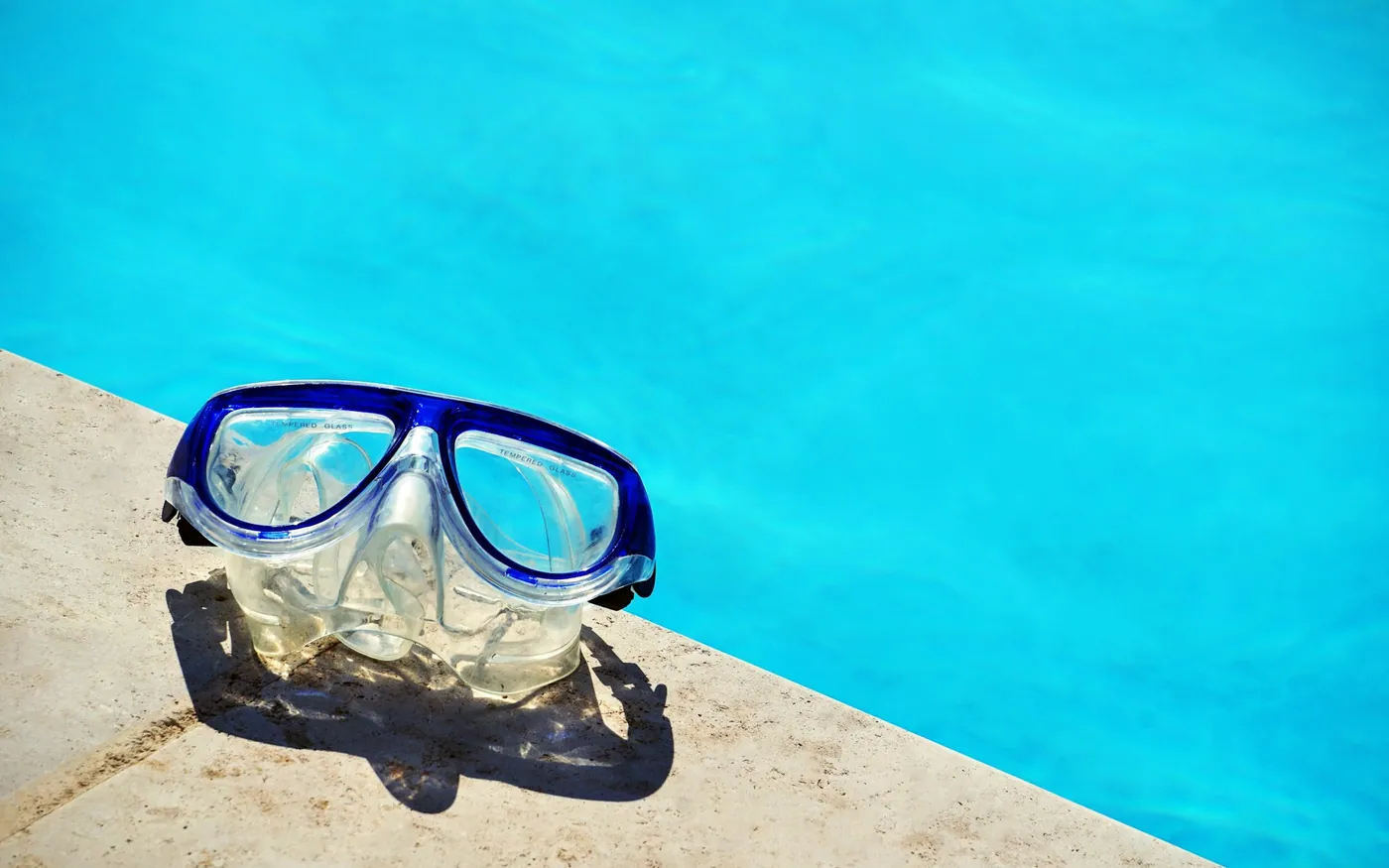 A scuba mask resting on the tiled edge of a pool before a session
