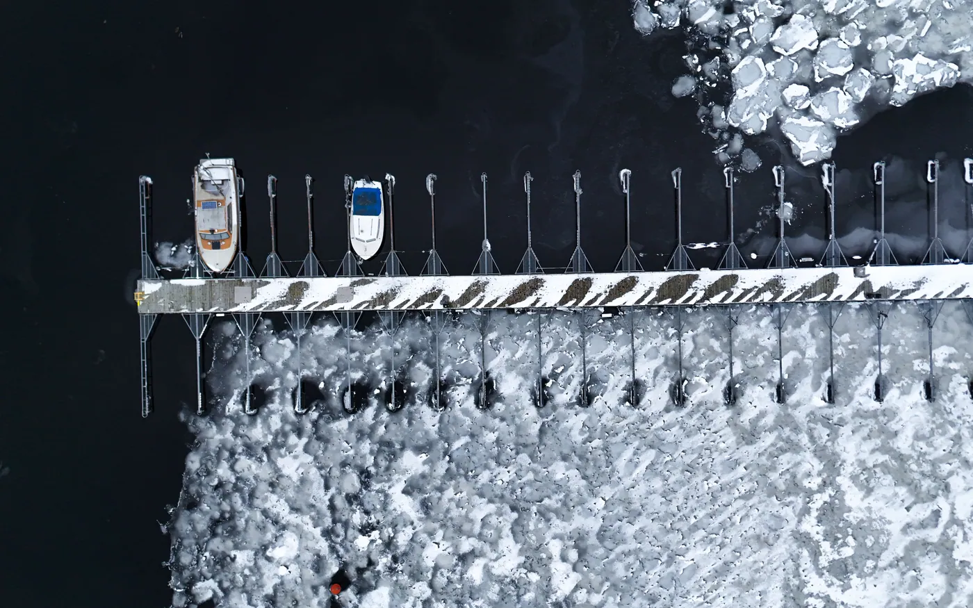 Snow lying on a marina dock with boats laid up