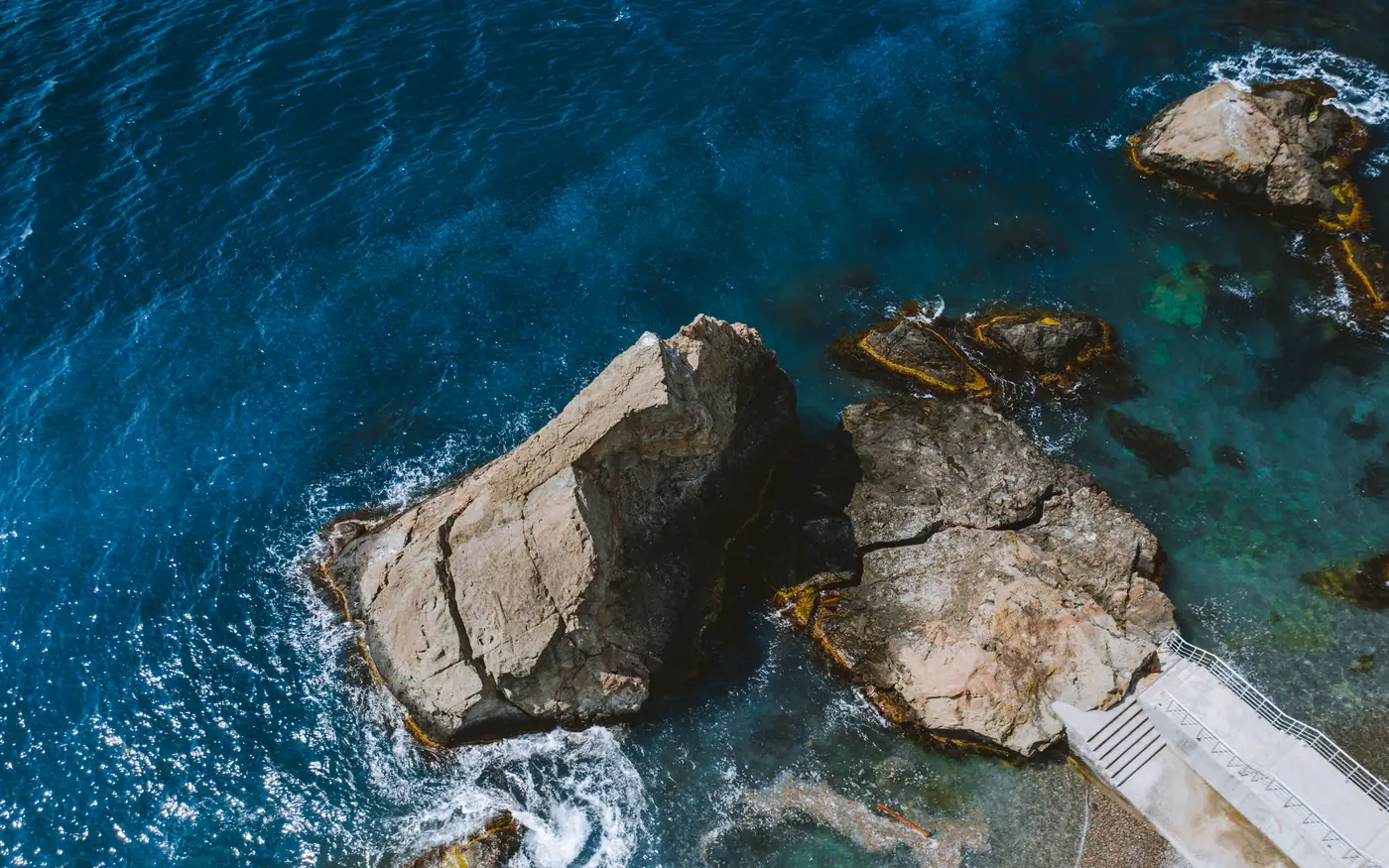 Concrete steps leading down into the sea between rocks