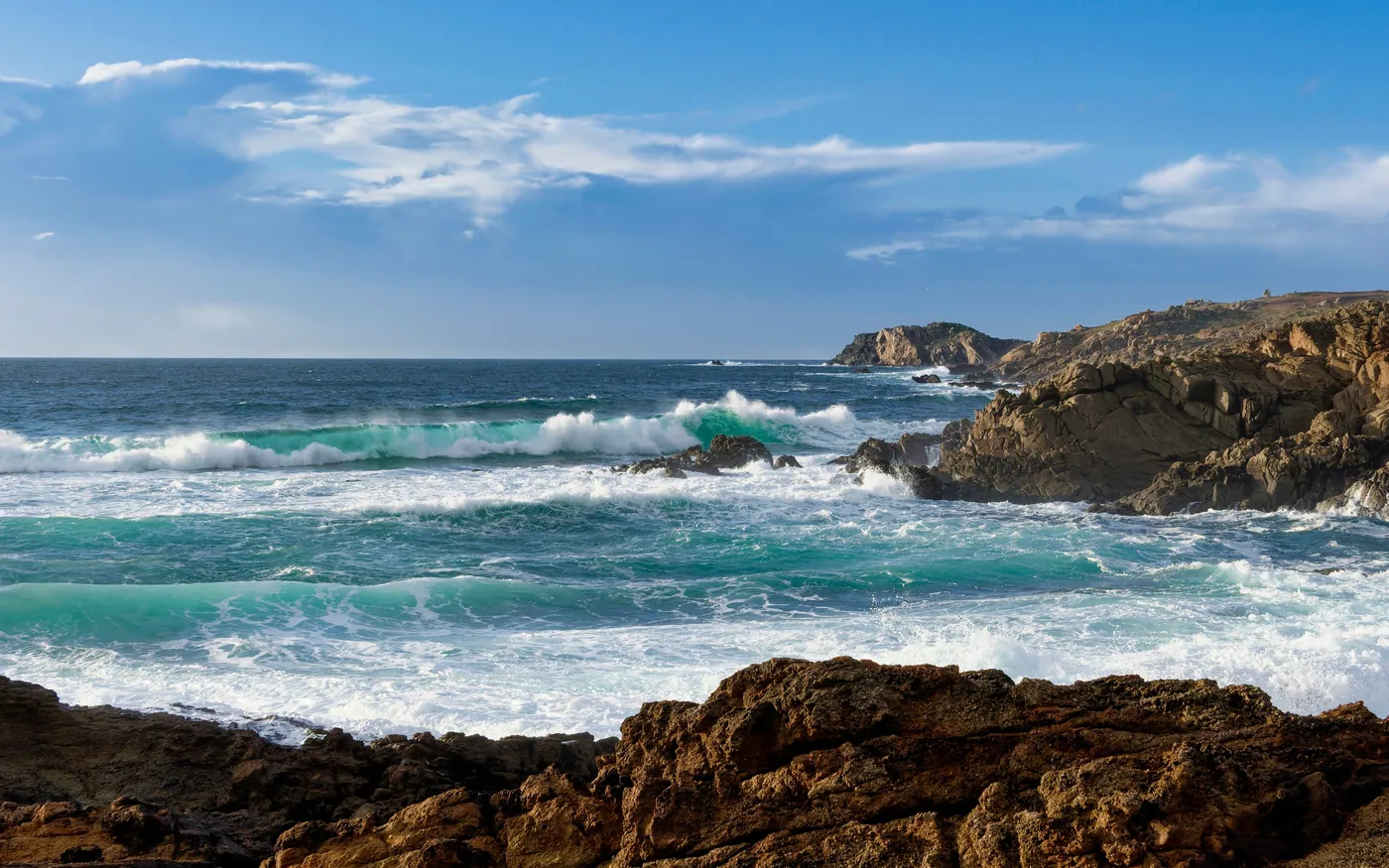 Summer surf breaking along a rocky coast