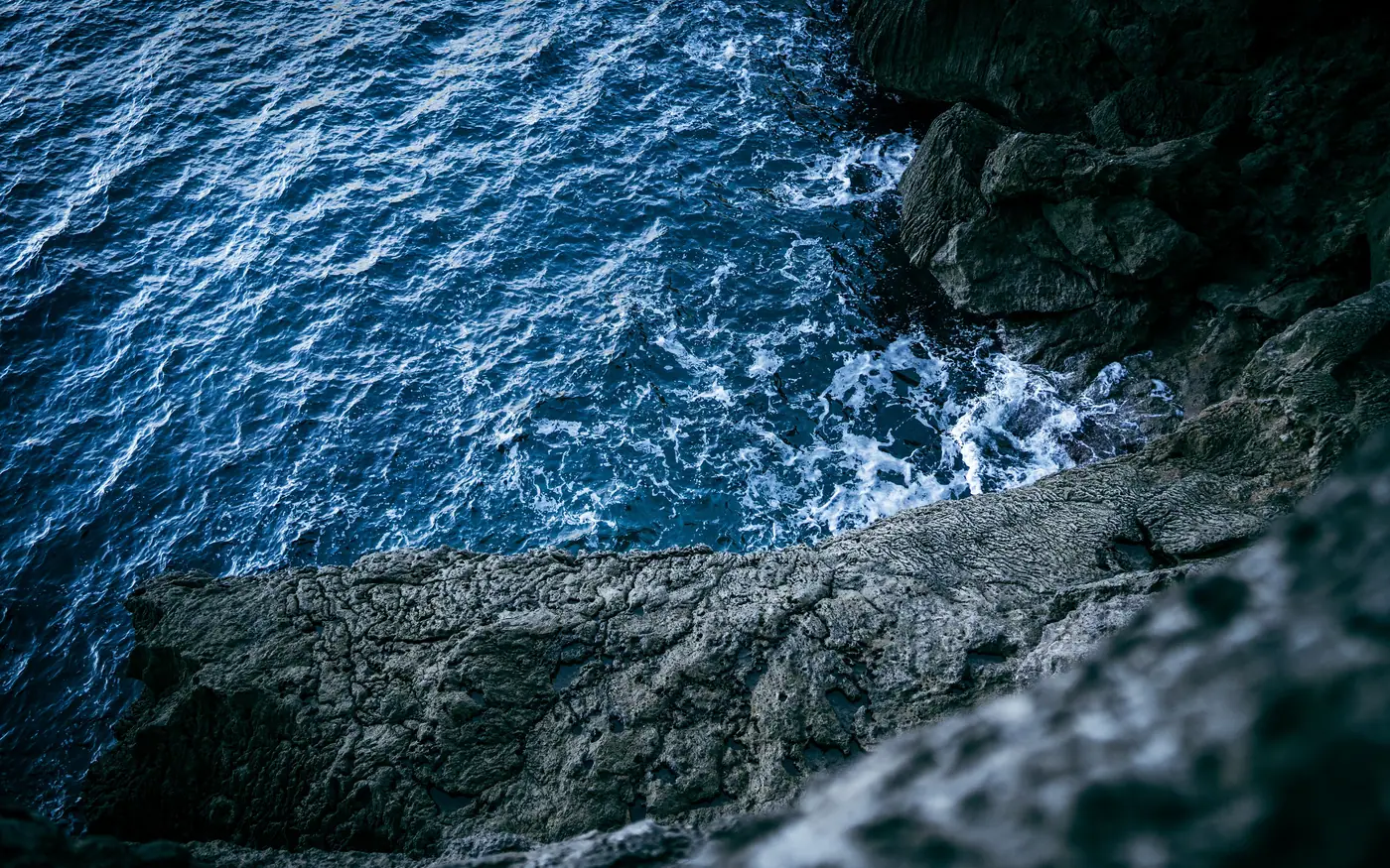 Surf breaking over dark rocks, the kind of day that stirs up visibility