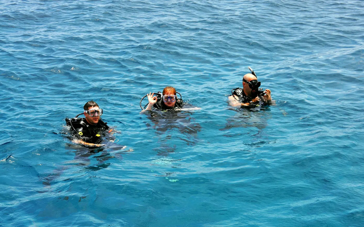 Three scuba divers floating together at the surface before a dive
