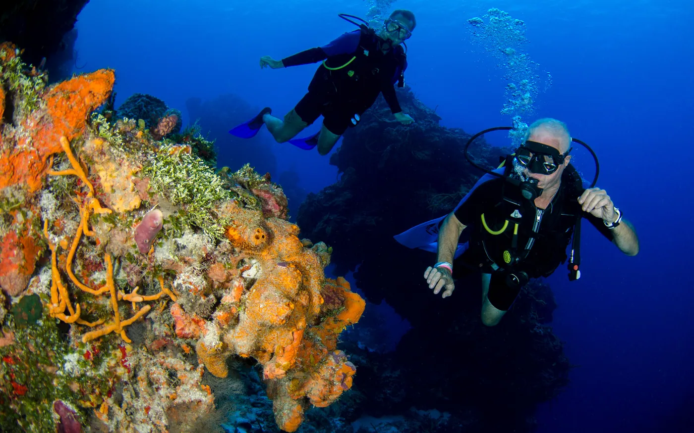 Two scuba divers drifting together above a reef