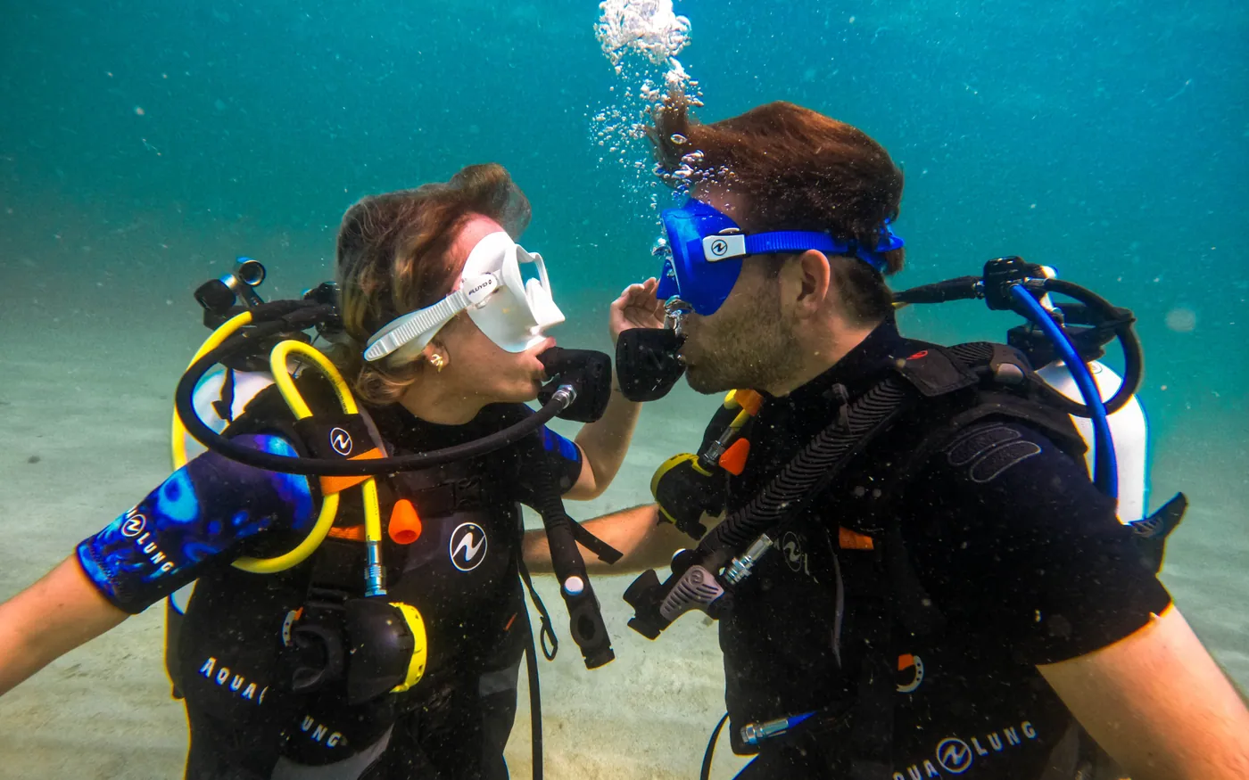 Two scuba divers facing each other underwater, communicating