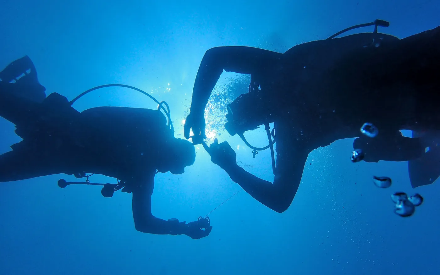 Two scuba divers silhouetted against deep blue open water