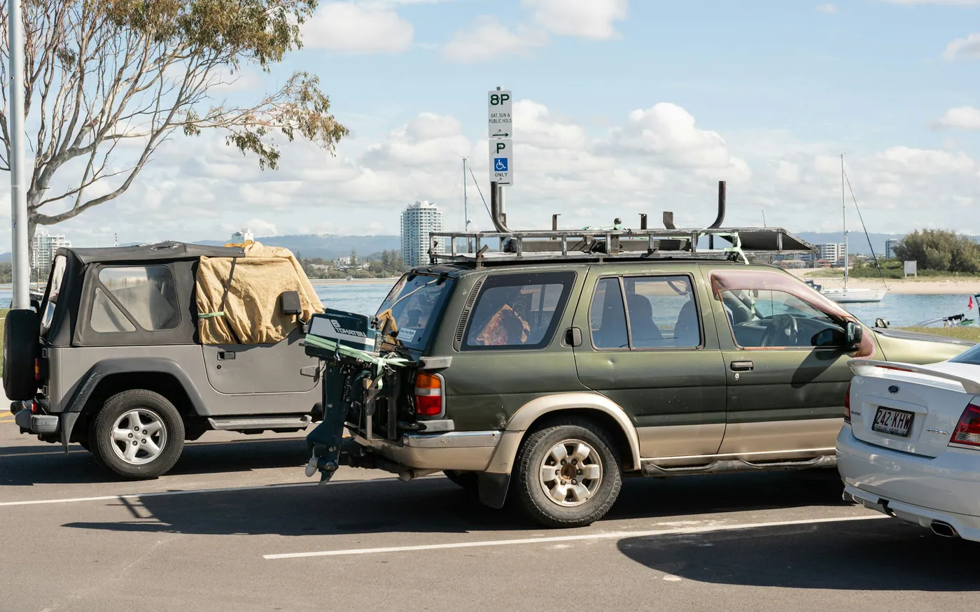 Vehicles parked beside the water with roof racks and equipment