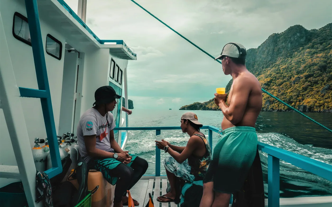 Divers sitting on a boat deck with equipment ready before a dive