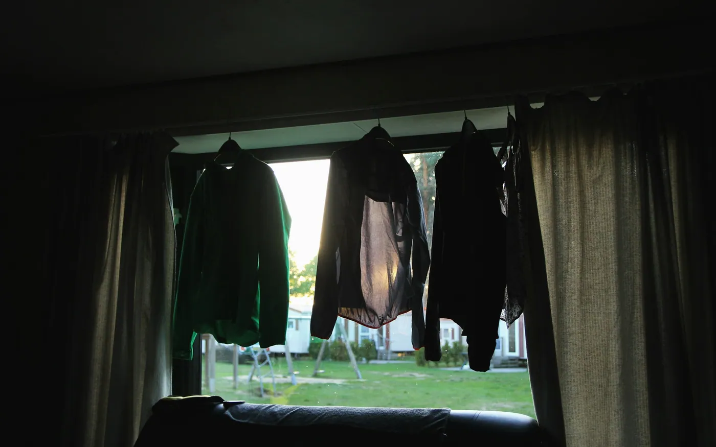 Wetsuits hung to dry in an open doorway out of direct sunlight