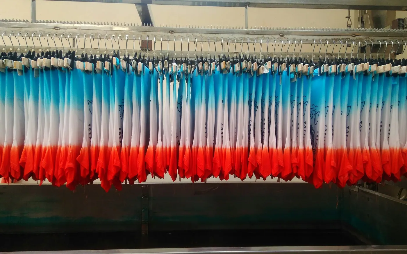 A long rail of wetsuits stored on hangers rather than folded