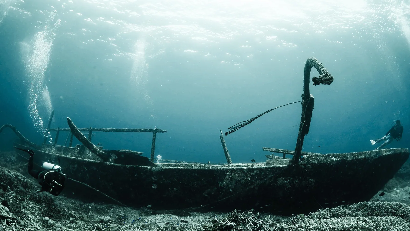 A diver alongside the remains of a wooden vessel on the seabed